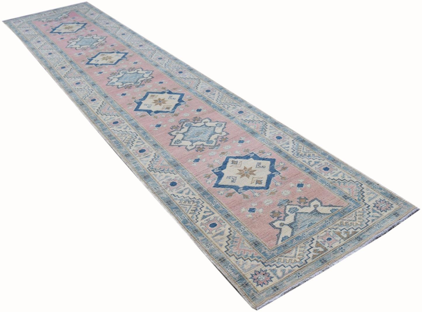 A handmade Afghan Kazakh runner rug featuring geometric patterns in soft pink and blue tones.