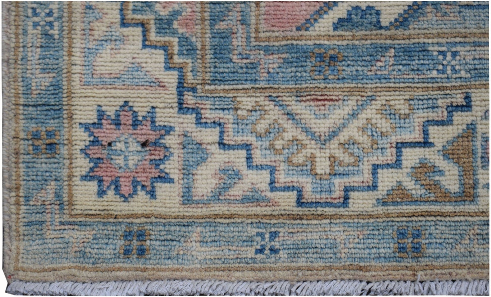 A handmade Afghan Kazakh runner featuring geometric patterns in blue, pink, and cream wool.