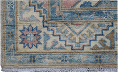 A handmade Afghan Kazakh runner featuring geometric patterns in blue, pink, and cream wool.