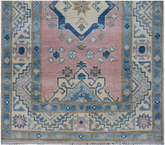 Handmade Afghan Kazakh runner featuring a geometric pattern in shades of pink, blue, and beige.