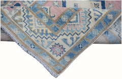 A handmade Afghan Kazakh runner featuring a geometric pattern in shades of blue, pink, and beige.