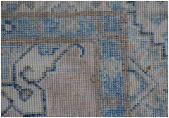 A close-up of an Afghan Kazakh runner rug featuring a geometric blue and beige pattern.
