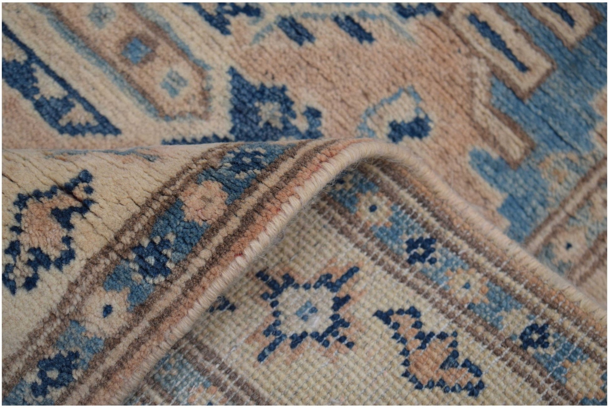 A handmade Afghan Kazakh runner featuring a traditional geometric pattern in beige and blue tones.