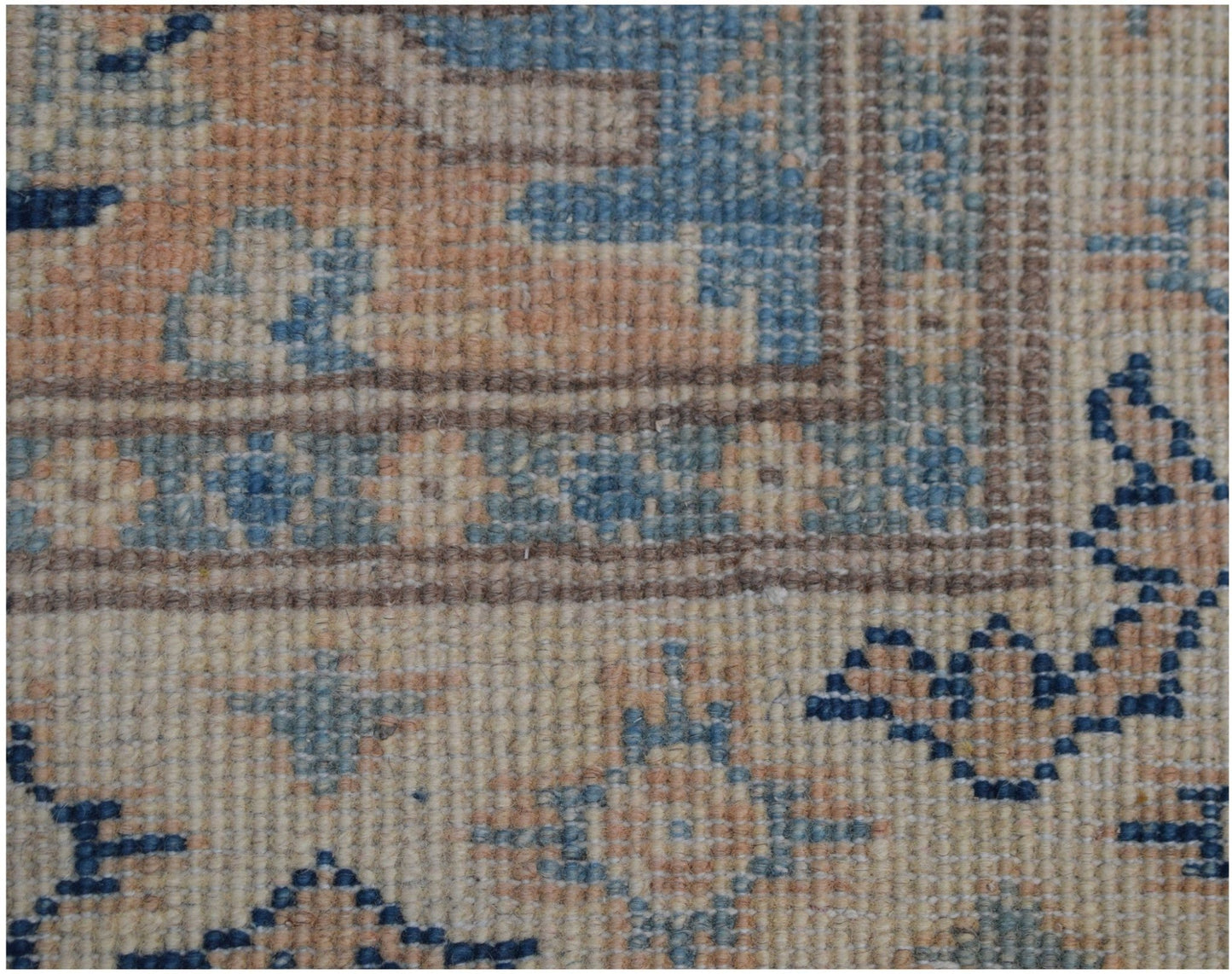 A close-up of a handmade Afghan Kazakh runner featuring a beige, blue, and grey geometric pattern.