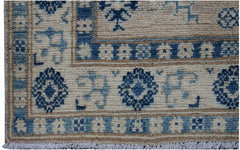 Handmade Afghan Kazakh runner rug featuring a geometric blue and beige pattern with fringe ends.