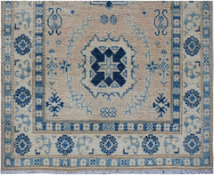 Handmade Afghan Kazakh runner featuring a central blue geometric medallion on a beige wool field.