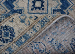 A handmade Afghan Kazakh runner featuring a blue and beige geometric pattern on a wool pile.
