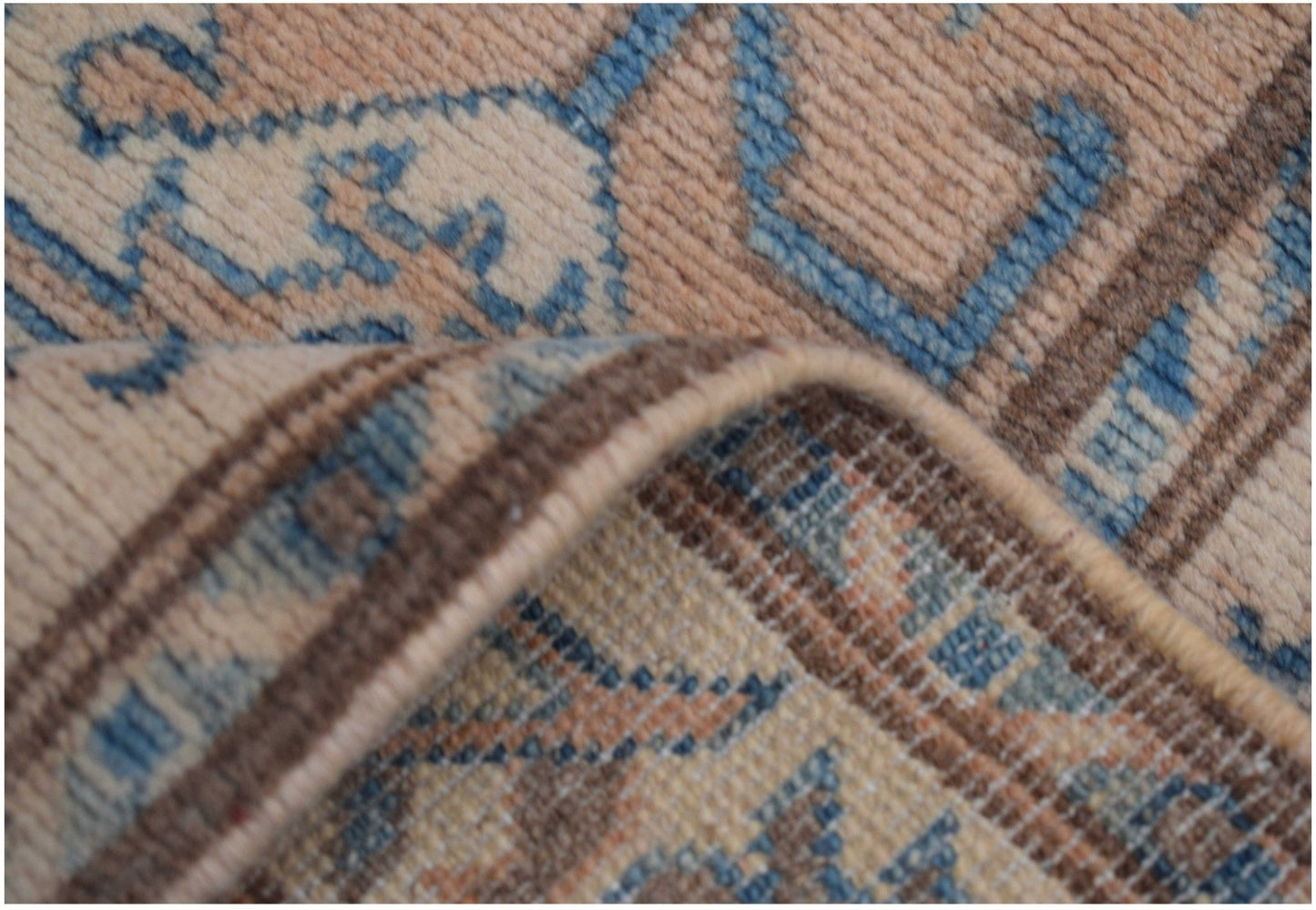 A close-up view of a handmade Afghan Kazakh runner featuring a beige, blue, and brown pattern.