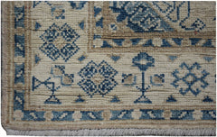 A handmade Afghan Kazakh runner rug featuring a beige field with blue geometric floral patterns.