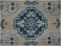 Handmade Afghan Kazakh runner featuring a central blue geometric medallion on a beige wool field.