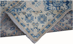 An Afghan Kazakh runner rug featuring a beige background with blue and grey geometric patterns.