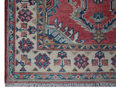 A handmade Afghan Kazakh runner featuring traditional geometric motifs in red, blue, and cream.