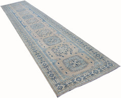 A long, handmade Afghan Kazakh runner rug featuring a beige field with blue geometric medallions.