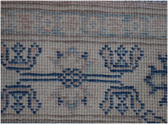A close-up of an Afghan Kazakh runner rug featuring a beige background with blue geometric motifs.