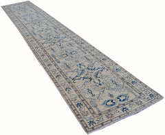 A long, handmade Afghan Kazakh runner rug featuring a beige field with blue and grey geometric motifs.