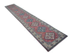 A handmade Afghan Kazakh runner rug featuring traditional geometric motifs in red, blue, and cream.