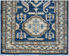 An Afghan Kazakh runner rug featuring a central geometric medallion in blue and beige tones.