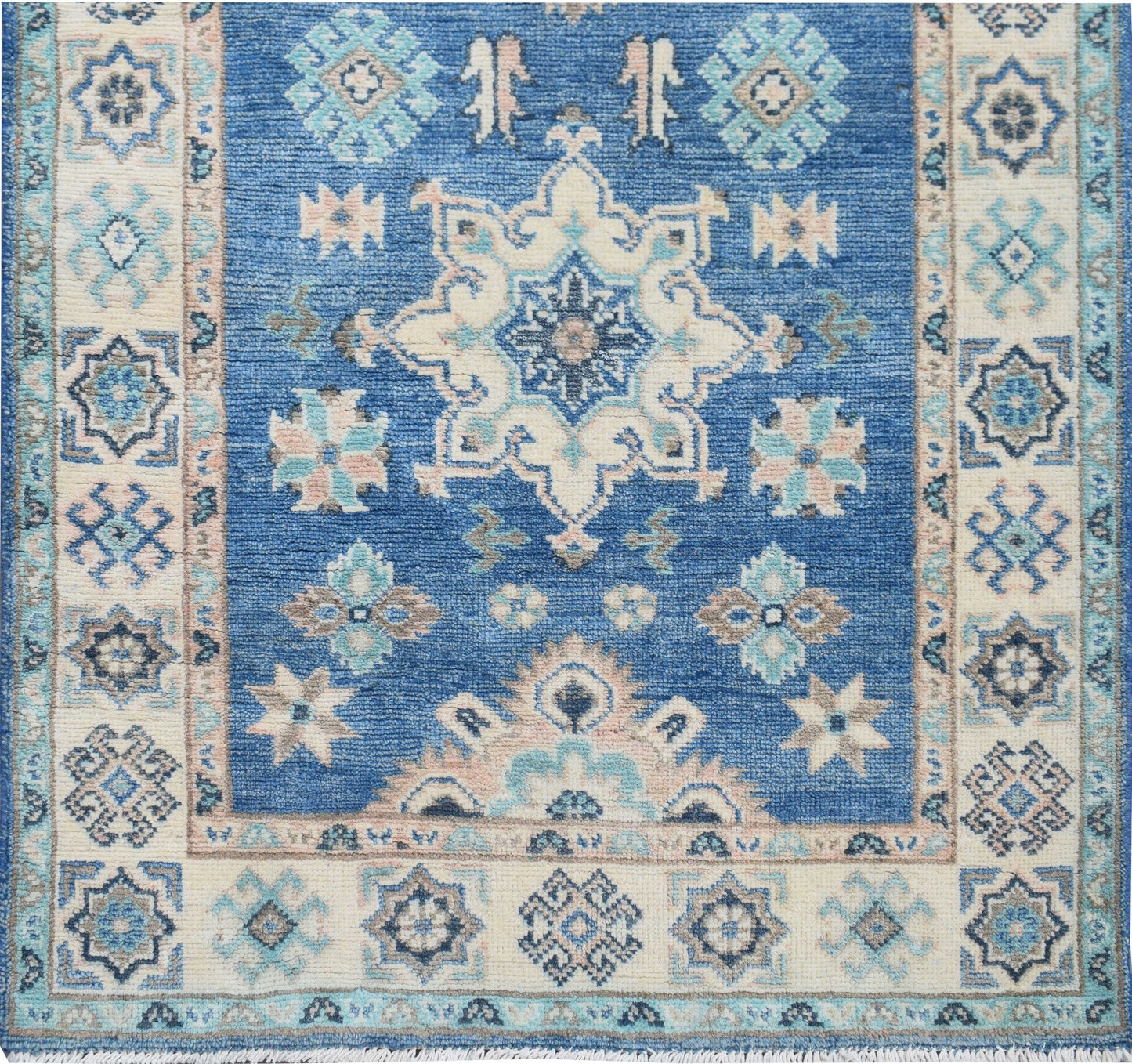 An Afghan Kazakh runner rug featuring a blue field with intricate beige and grey geometric patterns.