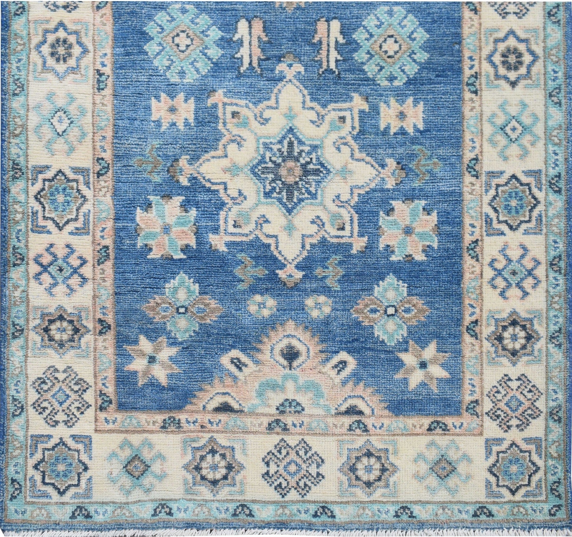 An Afghan Kazakh runner rug featuring a blue field with intricate beige and grey geometric patterns.