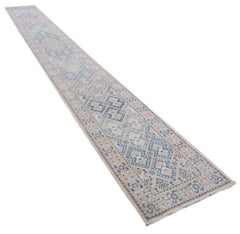 A long, handmade Afghan Kazakh runner rug featuring a geometric pattern in blue, beige, and grey.
