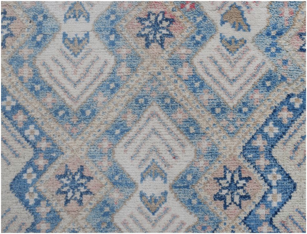 An Afghan Kazakh runner rug featuring a geometric diamond pattern in shades of blue, beige, and pink.