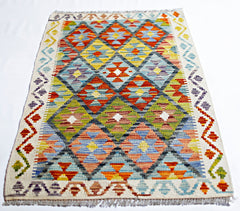 Handwoven Afghan Maimana kilim rug featuring a colorful geometric diamond pattern.