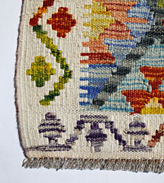A close-up of a handmade Afghan Maimana kilim featuring colorful geometric patterns on wool.