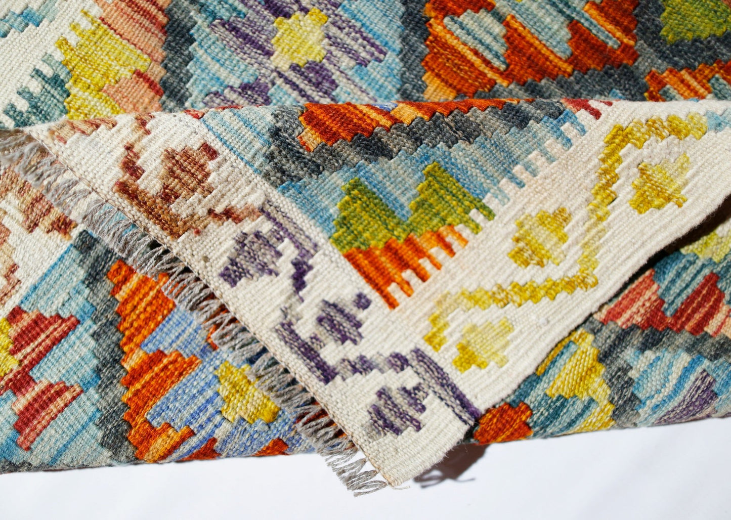 A handwoven Afghan Maimana kilim rug featuring a vibrant geometric pattern in wool.