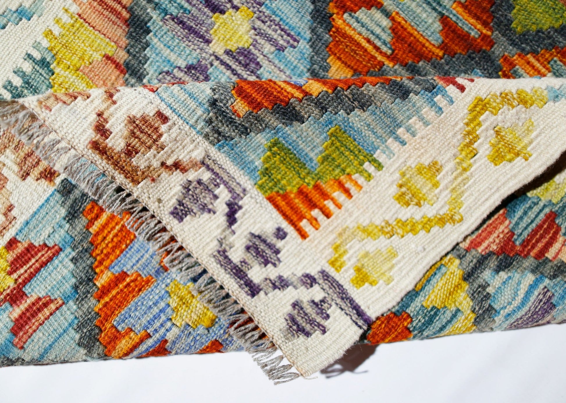 A handwoven Afghan Maimana kilim rug featuring a vibrant geometric pattern in wool.