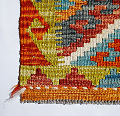 A close-up of a handmade Afghan Maimana kilim featuring vibrant geometric patterns in wool.