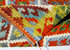 A folded handmade Afghan Maimana kilim rug featuring a vibrant geometric pattern in wool.