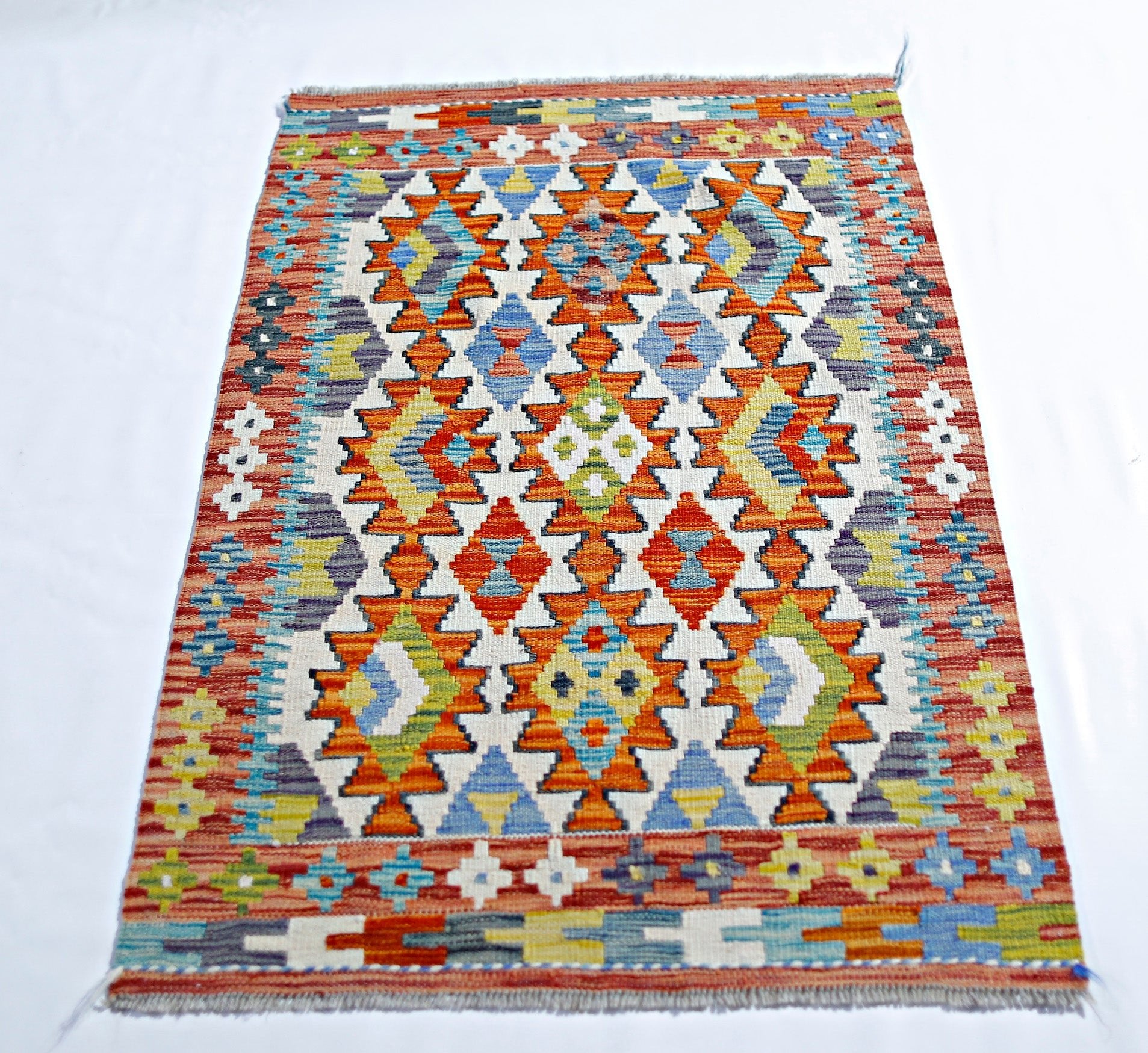 Handwoven Afghan Maimana kilim rug featuring a vibrant geometric pattern in wool.