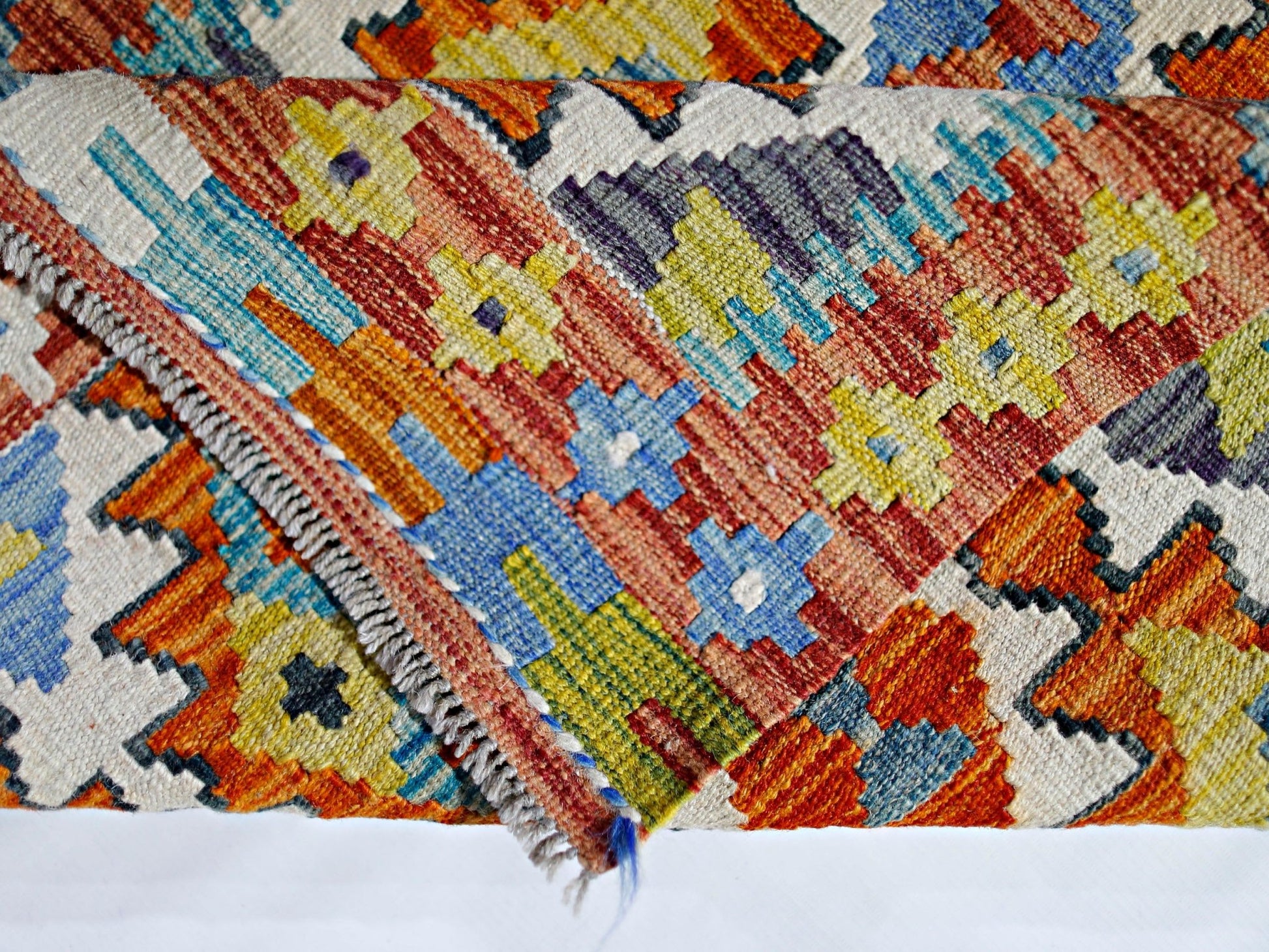A handmade Afghan Maimana kilim featuring a vibrant geometric pattern in wool.