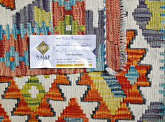 A handwoven Afghan Maimana kilim featuring a vibrant geometric pattern in wool.