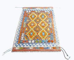 A rectangular Afghan Maimana kilim featuring a vibrant geometric pattern in wool.