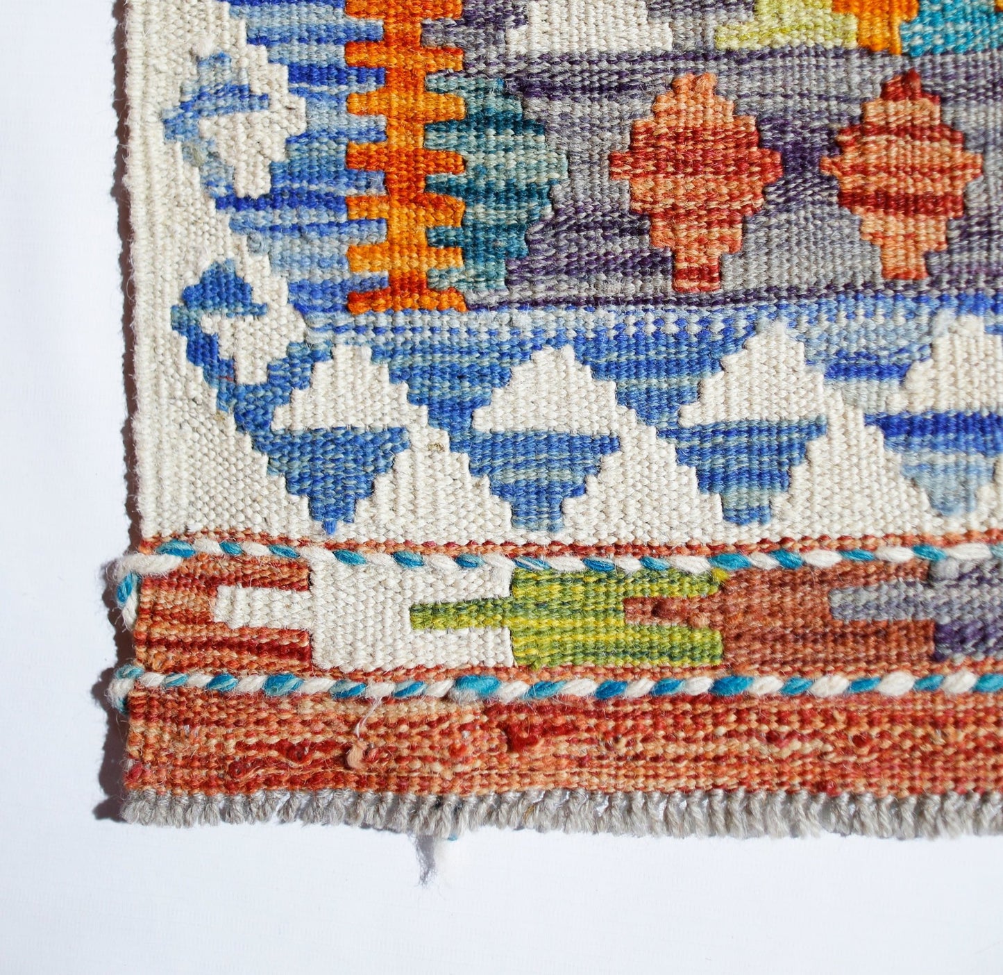 Handwoven Afghan Maimana kilim featuring a geometric pattern in vibrant orange, blue, and green.