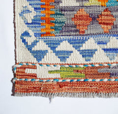 Handwoven Afghan Maimana kilim featuring a geometric pattern in vibrant orange, blue, and green.