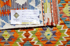 A handwoven Afghan Maimana Kilim featuring a vibrant geometric pattern in orange, green, and blue.