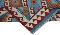 A handmade Afghan Maimana kilim rug featuring geometric patterns in red, blue, and orange wool.