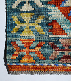 A close-up of a handmade Afghan Maimana kilim featuring geometric patterns in blue, orange, and tan.