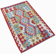 Handwoven Afghan Maimana kilim rug featuring a geometric pattern in red, blue, and cream wool.