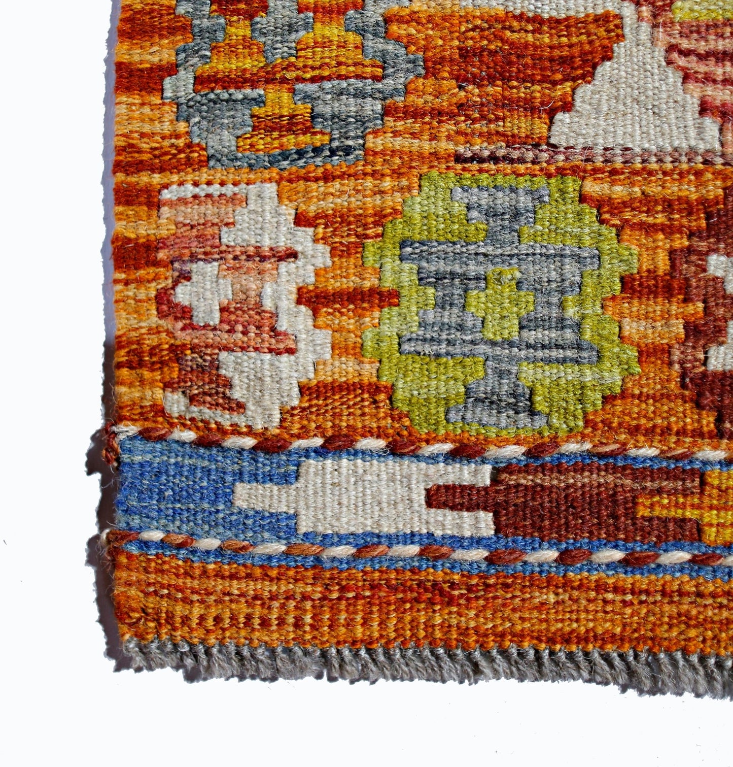 A close-up of a handmade Afghan Maimana kilim featuring geometric patterns in orange and green.