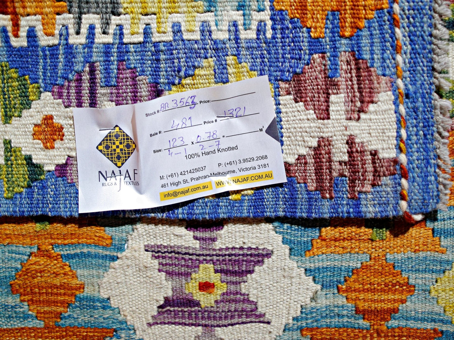 A handwoven Afghan Maimana kilim featuring vibrant geometric patterns in blue, orange, and purple.