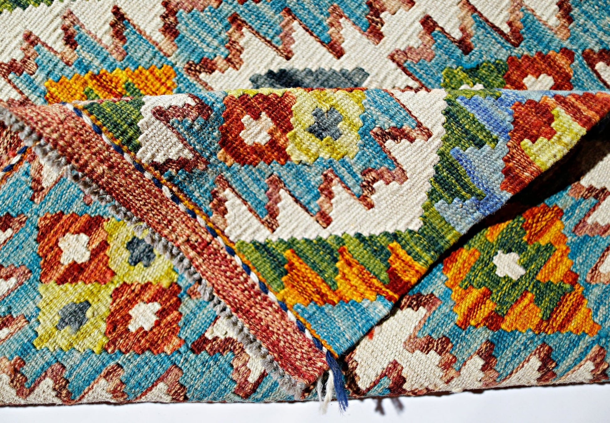 A handwoven Afghan Maimana kilim rug featuring vibrant geometric patterns in wool.