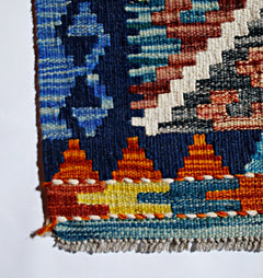 A close-up of a handmade Afghan Maimana kilim featuring geometric patterns in vibrant wool colors.
