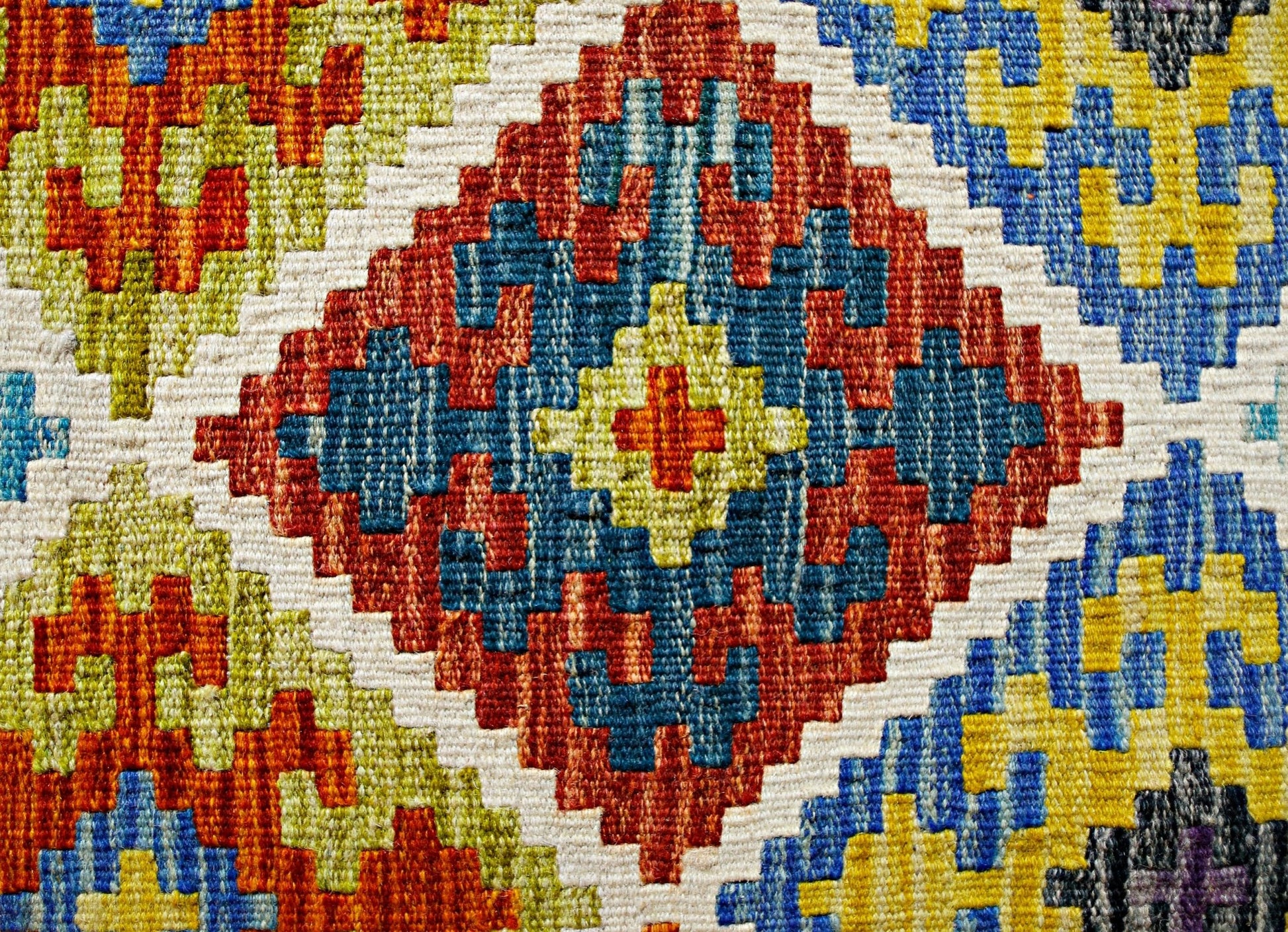 Handwoven Afghan Maimana kilim featuring a vibrant geometric pattern in red, blue, and yellow.
