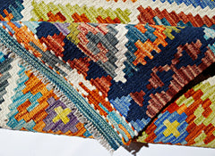 A handwoven Afghan Maimana kilim rug featuring a vibrant geometric pattern in wool.