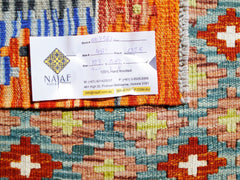 A handmade Afghan Maimana Kilim rug featuring a geometric pattern in orange, blue, and green.