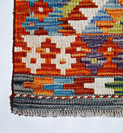 Handwoven Afghan Maimana kilim featuring a vibrant geometric pattern in wool.
