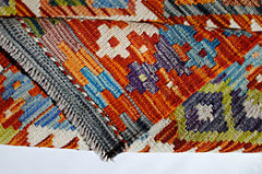 A handwoven Afghan Maimana kilim featuring a vibrant geometric pattern in wool.